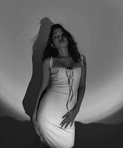 Black and white portrait in a white dress under a spotlight