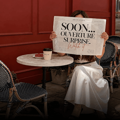 Woman reading a newspaper at a café table