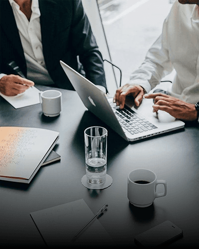 Two people working at a laptop over coffee